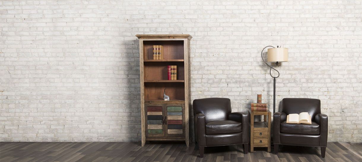 A bookcase and two leather armchairs against a white brick wall